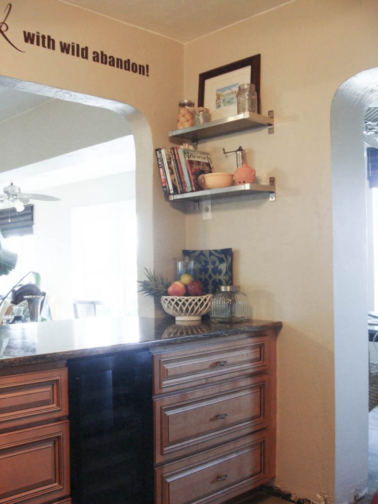 kitchen cabinets with pass through to living room and shelves on the wall to organize a small kitchen