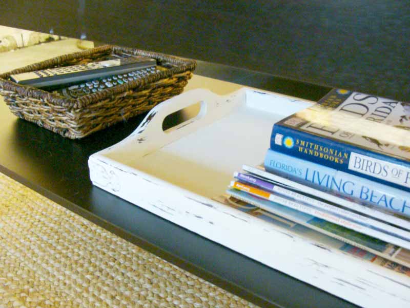 basket of remotes and tray of magazines and books on shelf under coffee table