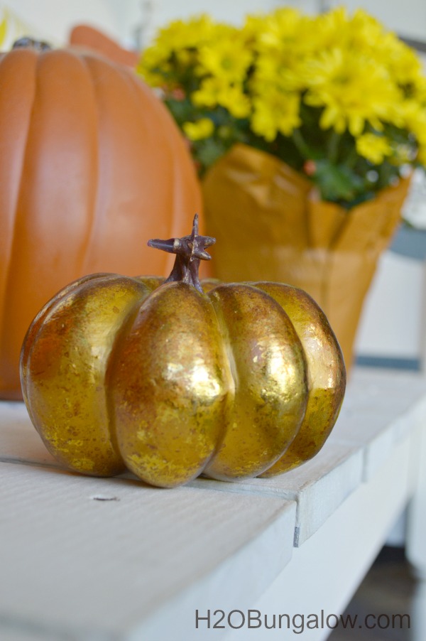 close up of gold pumpkin sitting on white bench