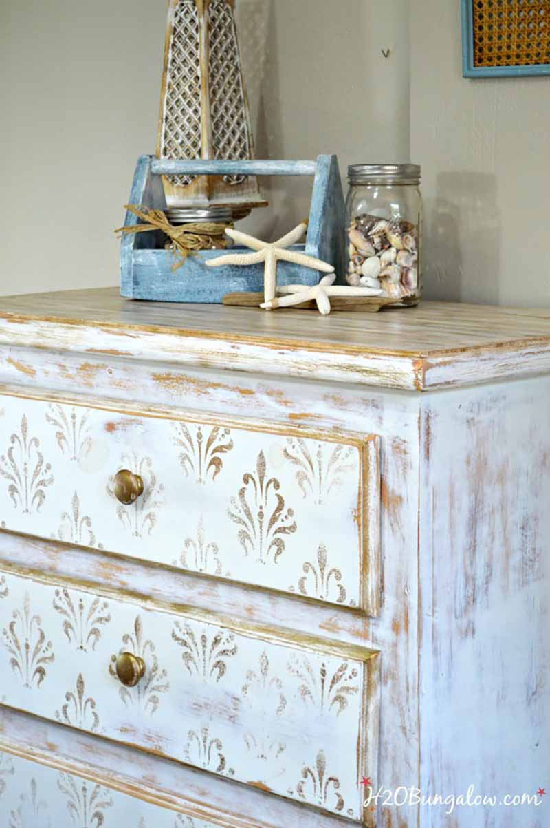 white distressed painted dresser with star fish and seashells in a jar on top 