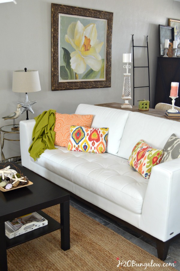 White leather sofa with colorful throw pillows and coffee table