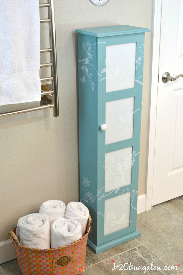 Updated bath storage cabinet with DIY frosted glass inserts and cascading stenciled birds and twigs. It looks fresh and clean look in our new master bath www.H2OBungalw.com #ThemedFurnitureMakeoverDay #painted