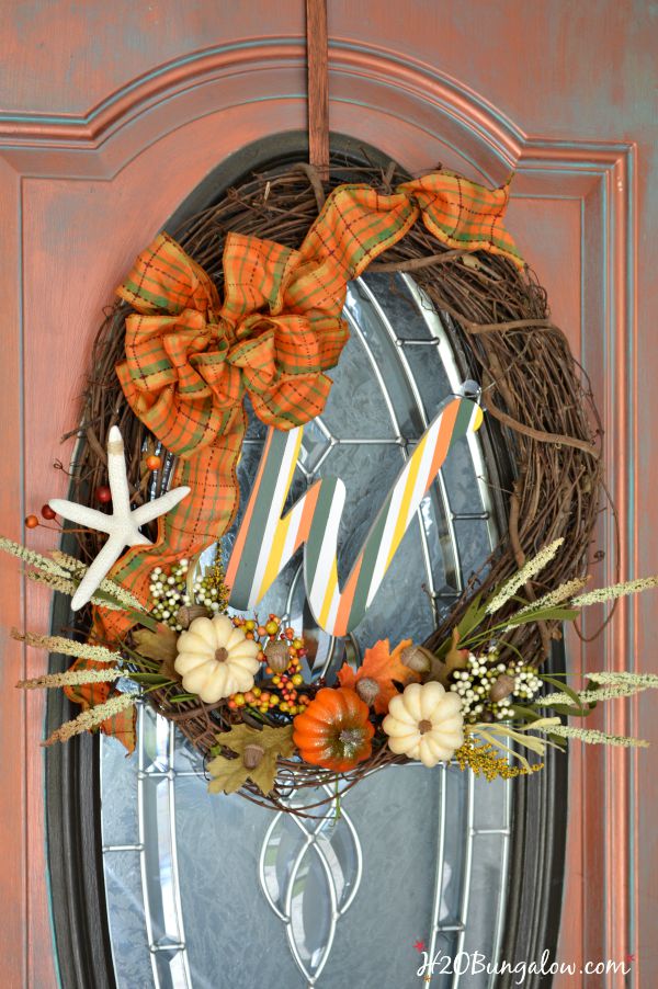 Make a simple and festive monogram fall wreath with starfish, acorns and pumkins. Tuck sprigs of greenery into the grapevine wreath for filler. See this and 30 more fall projects in the Fall Ideas Tour. www.H2OBungalow.com #Fallwreath "Falldecor #FallIdeasTour