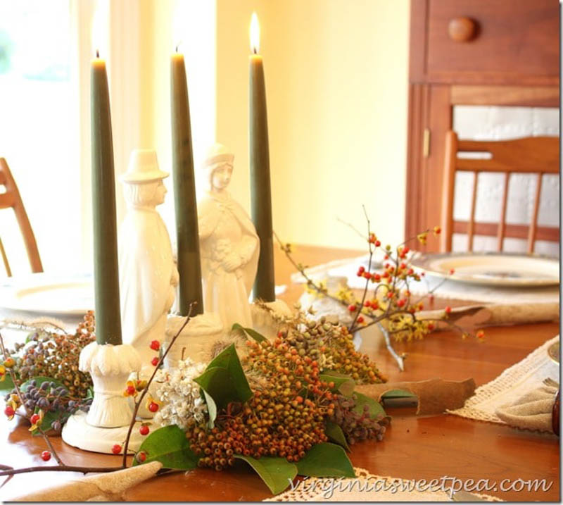 3 candlestick holders and fall floral with pilgrims as the centerpiece