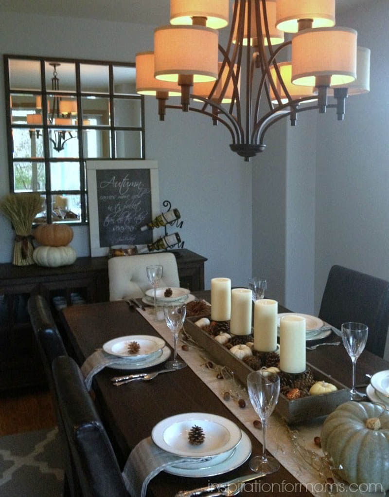 pinecones, pumpkins and candles in a wood box on a table runner