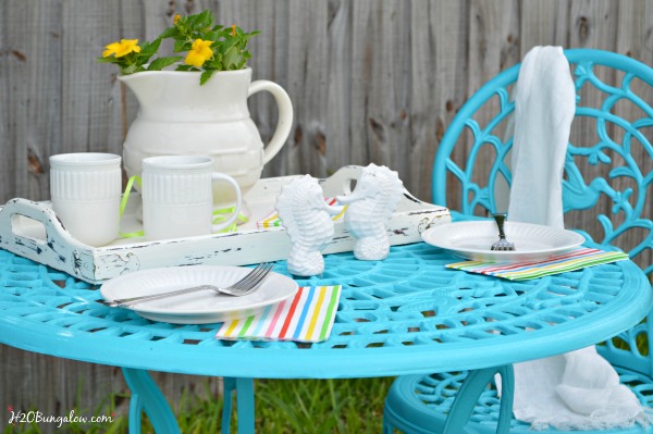 Close up of outdoor metal table and chair set spray painted turquoise with table settings for two