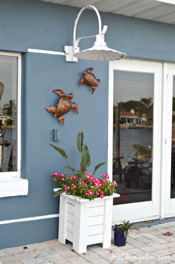 outdoor metal turtles hung on blue house with white planter