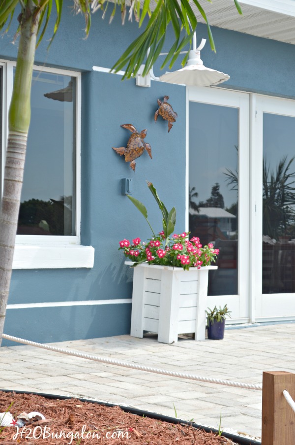 metal turtles hung on blue house with white planter