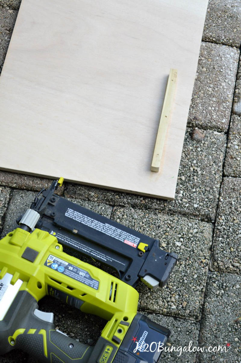 board laying on brick with nail gun