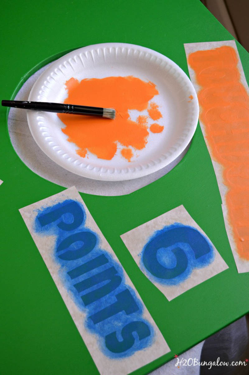 orange stencil paint on paper plate blue painted stencil on green board