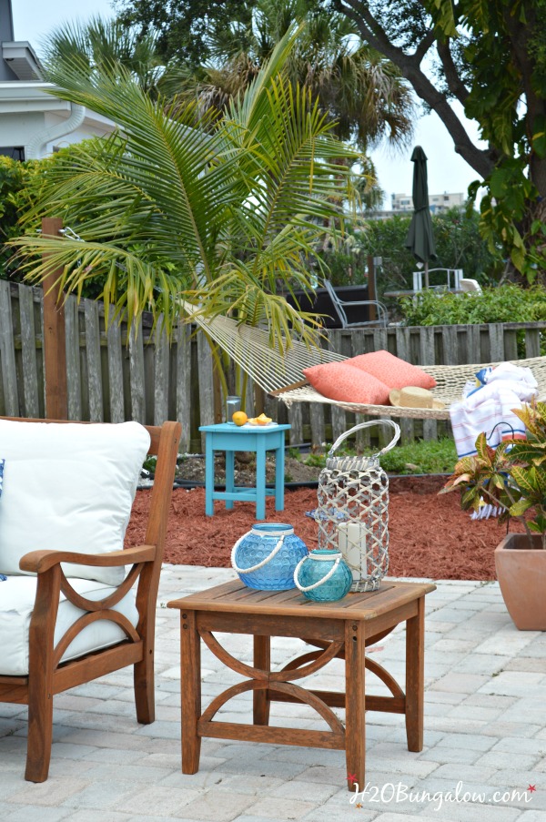 outdoor patio with teak side table and chair and DIY hammock stand in the back