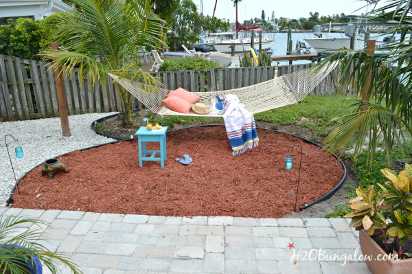 Hammock in the landscaped area with turquoise side table and coral colored pillows