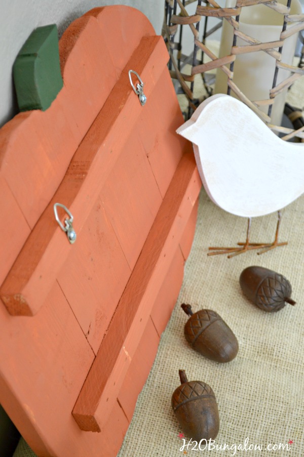 back side of wood pumpkin cutout painted orange with white wood bird and acorns