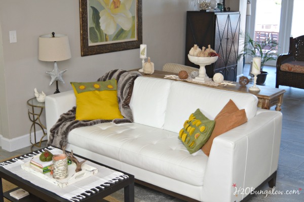 White leather sofa with green and yellow throw pillows and coffee table