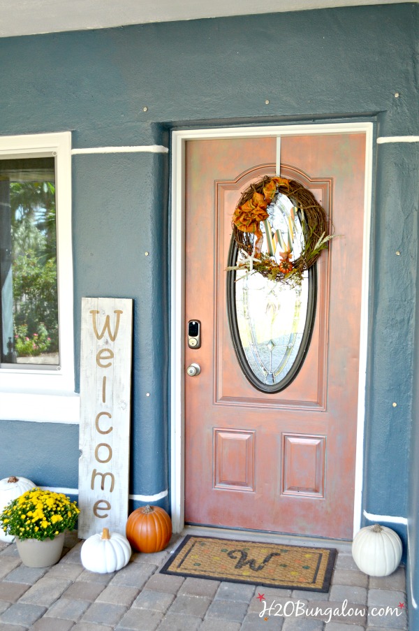 Large DIY wood welcome sign on the front porch with pumpkins and yellow mums