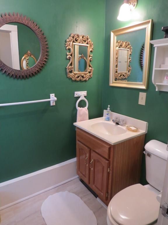 bathroom before update with green painted walls, mirrors and old fixtures