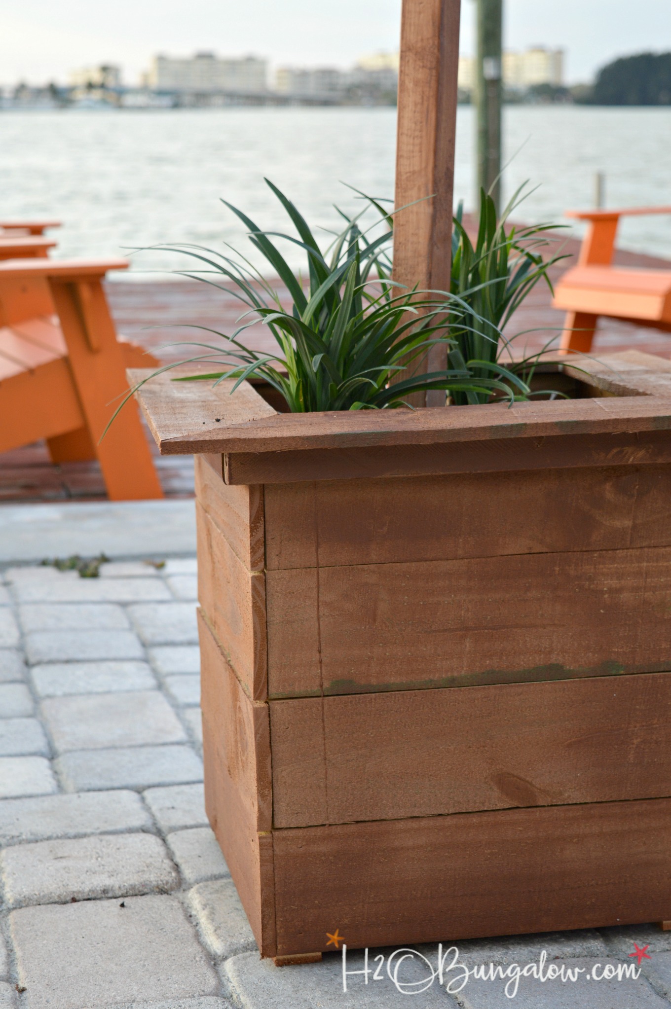 DIY outdoor cedar box shown with plants and pole for outdoor string lights.