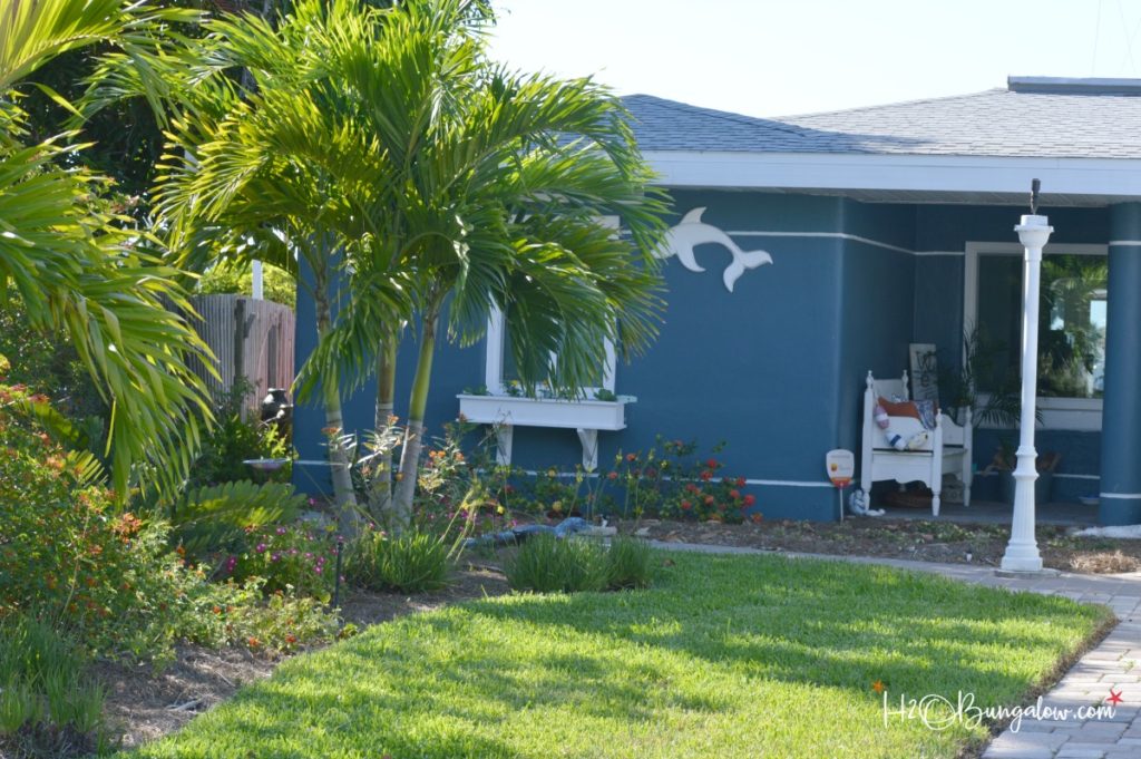 front of house with palm trees and butterfly garden