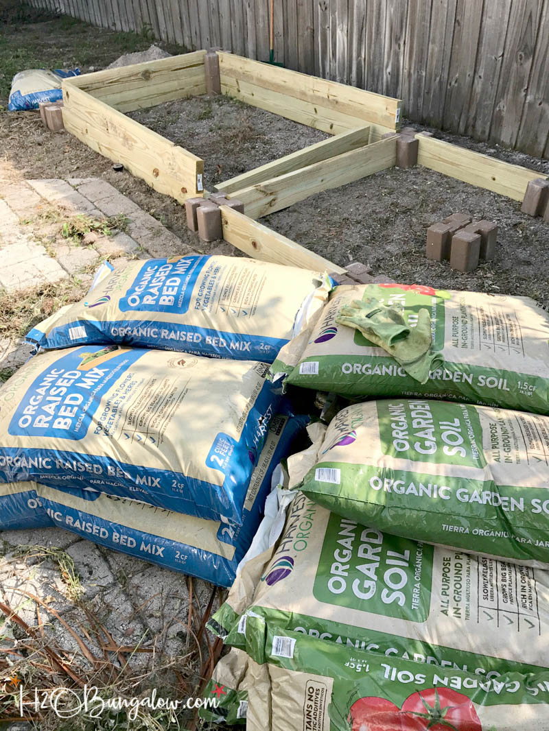 bags of organic soil laying next to completed raised garden bed frames