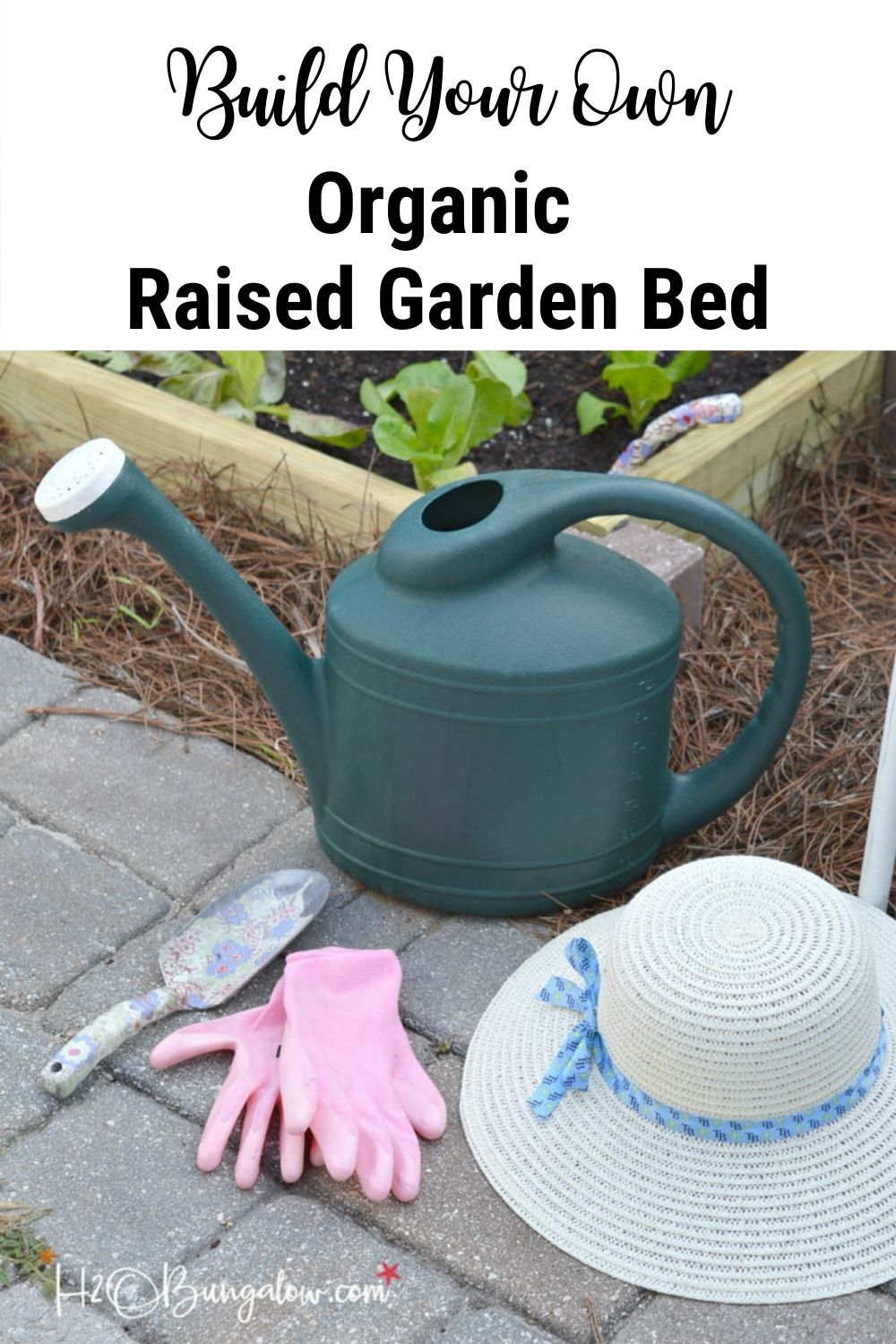 watering can, hat, pink gardening gloves and spade in front of raised garden bed