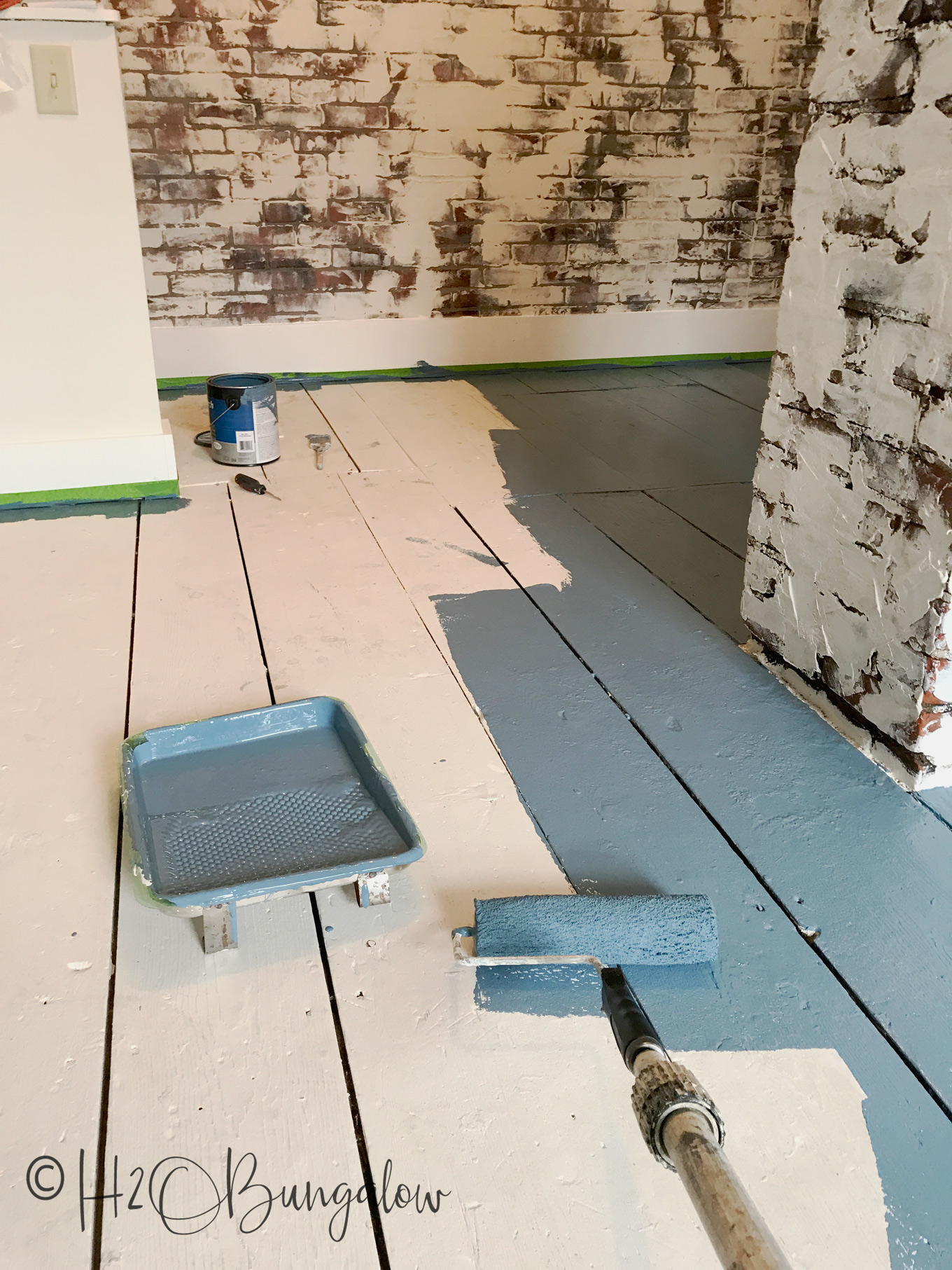 wood floor shown with white primer and gray paint on half with paint roller