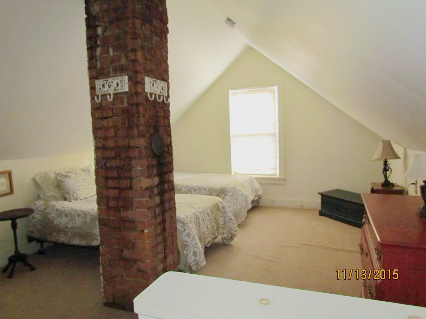 Loft bedroom with brick chimney and two twin beds against the wall
