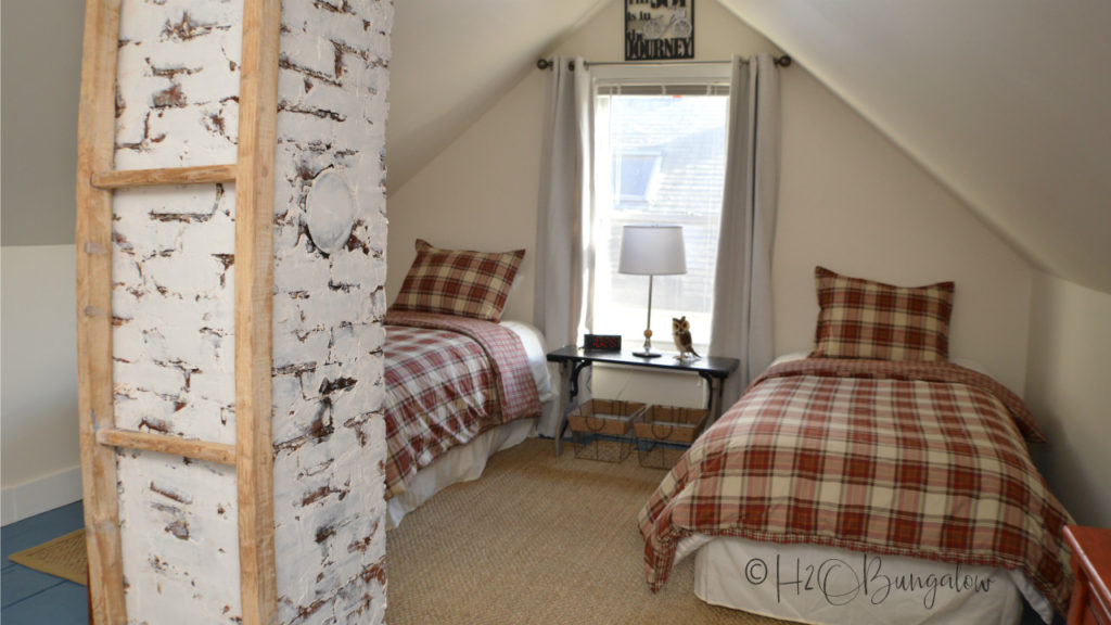 two beds on each side of a window with red checked bedspreads and brick chimney column done with german schmear technique