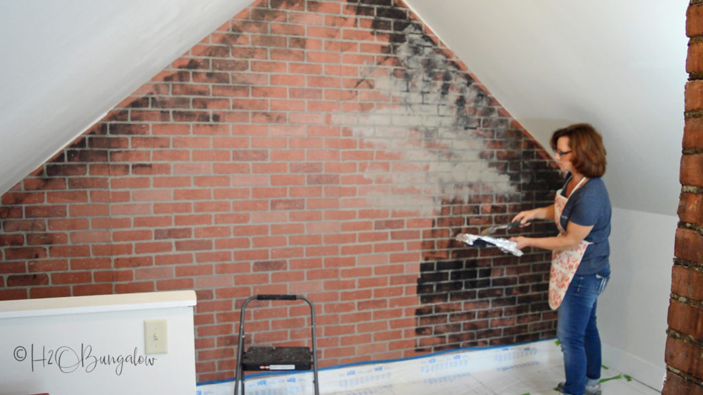 Wendi standing in front of partially cleaned brick wall in a loft