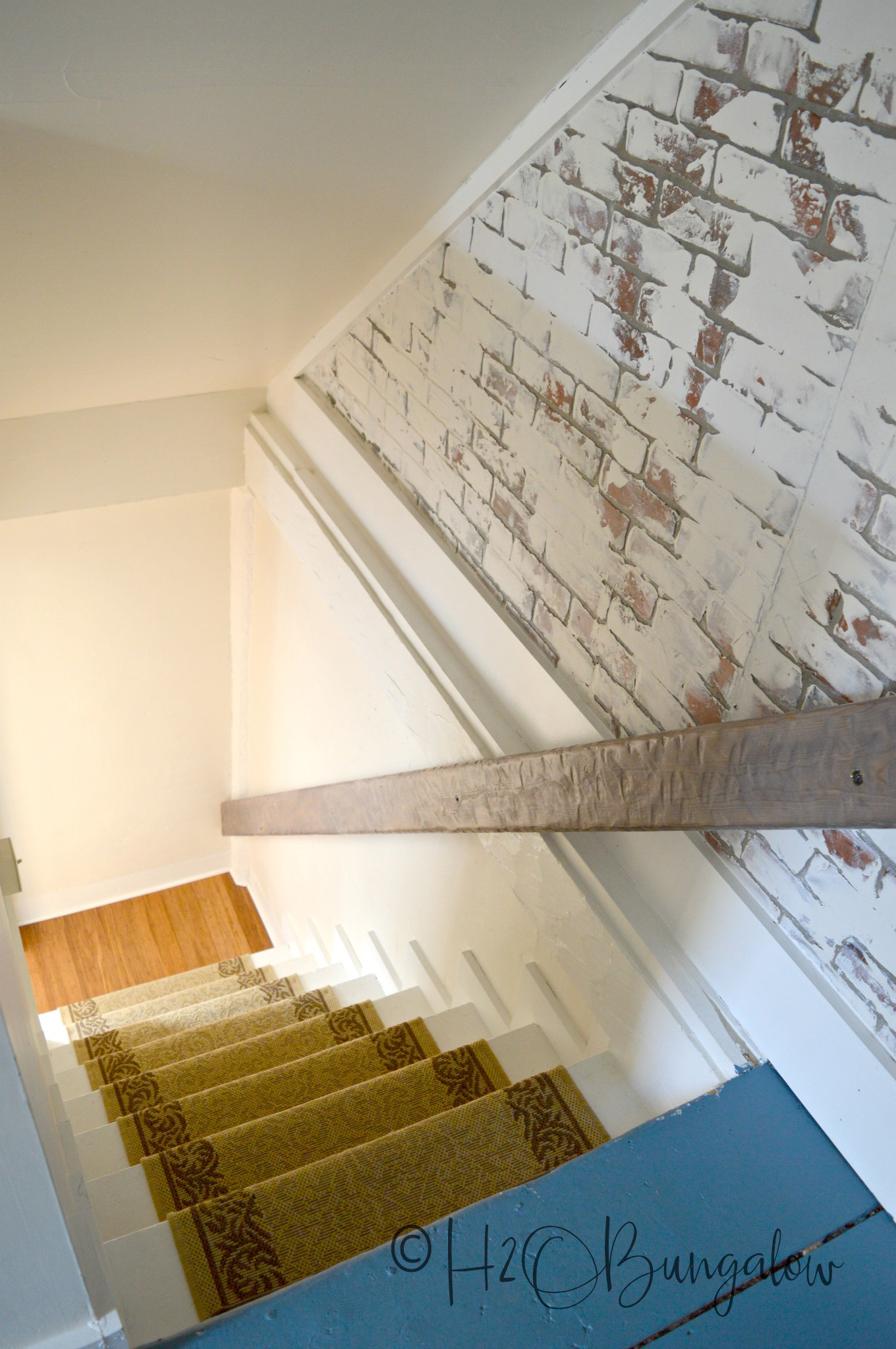 Stairwell to loft with rug runner on steps and brick painted with German schmear technique