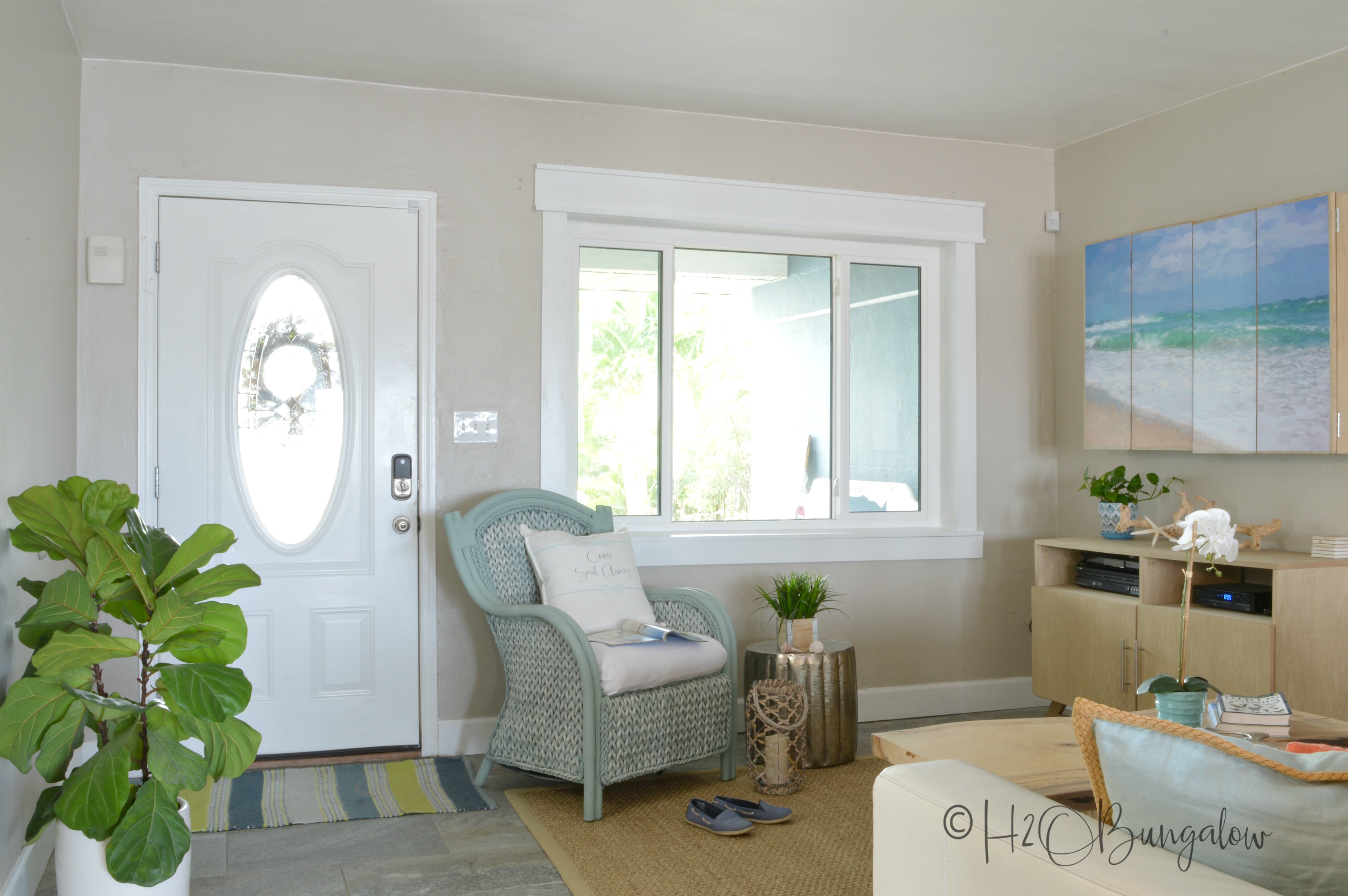 DIY craftsman style window shown with trim in living room with white door and blue chair. 