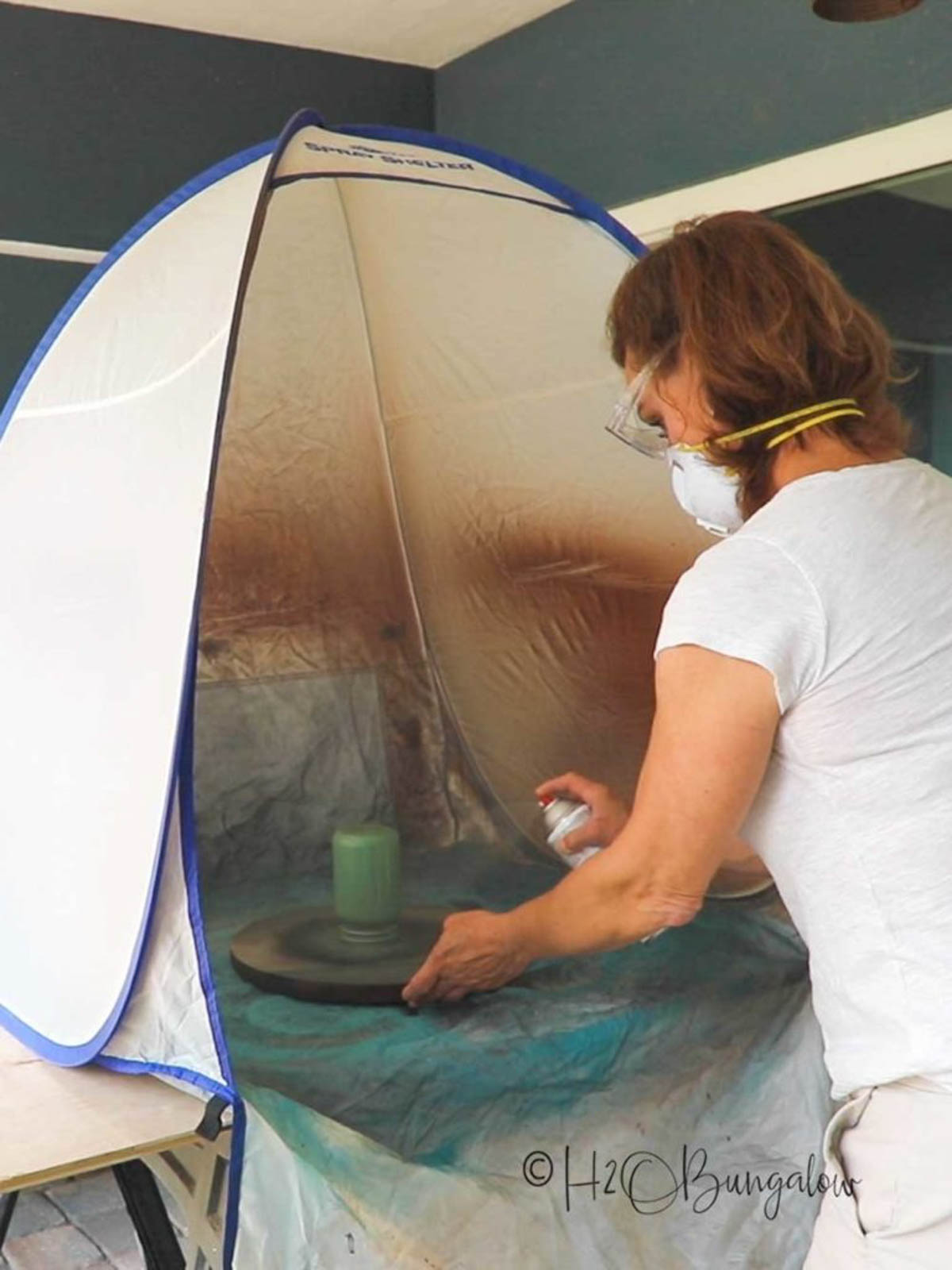 painting glass jars with spray paint in small paint shelter