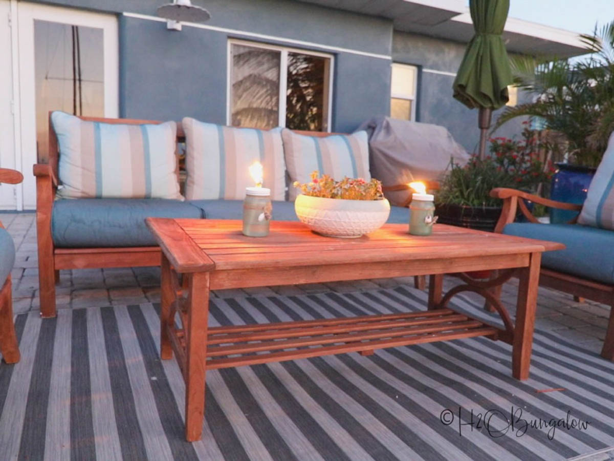 outdoor seating area with sofa and coffee table with DIY tiki torches