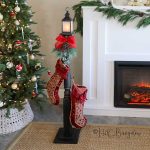 completed DIY stocking holder stand with stockings in front of the Christmas tree and fireplace