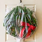 Christmas wreath with red bow in plastic bag hanging on a hook for storage