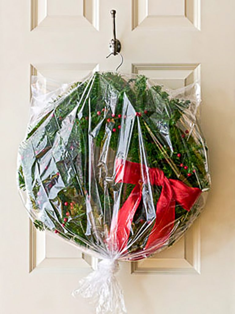 Christmas wreath with red bow in plastic bag hanging on a hook for storage