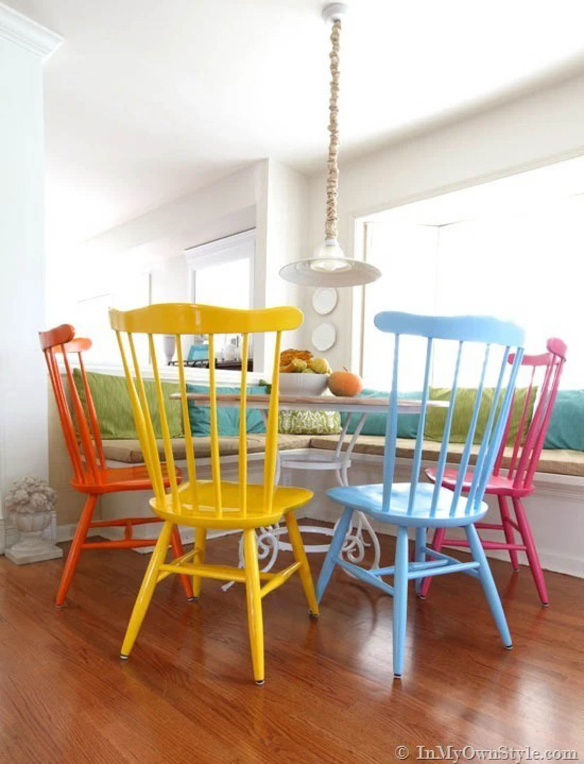 spray painted chairs in yellow, red and blue around a dining room table