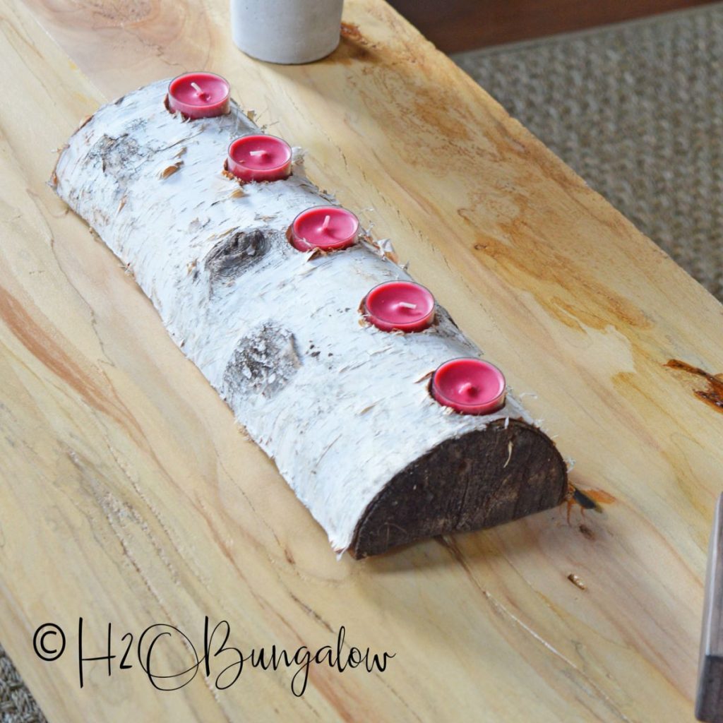 Birch log with five red tea lights sitting on wood coffee table