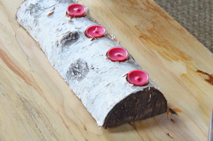Birch log with five red tea lights sitting on wood coffee table