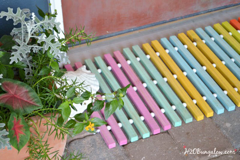 woodworking gift idea doormat made from wood painted pink, green, blue and yellow