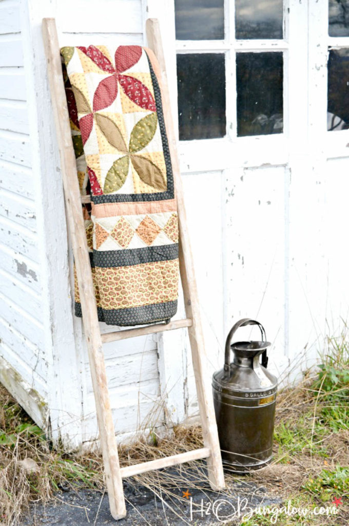 DIY wooden ladder with quilt hanging on it leaning against the outside of a building