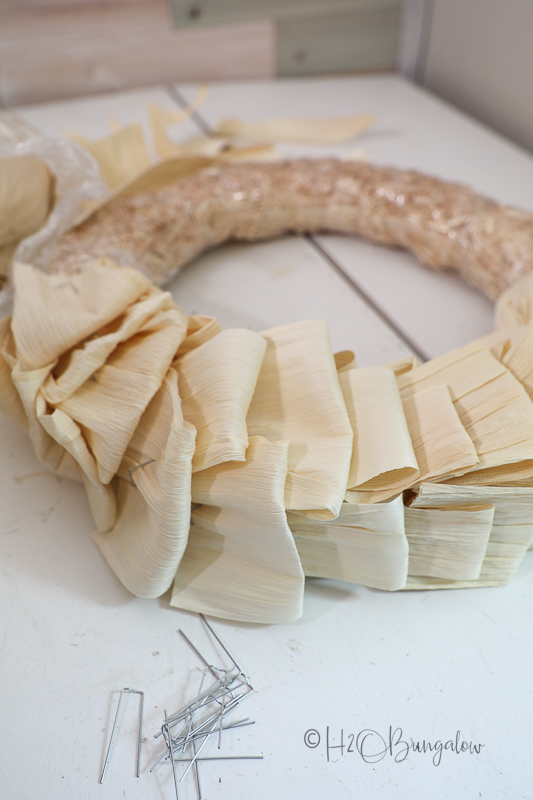 Layer corn husks onto wreath and pin 