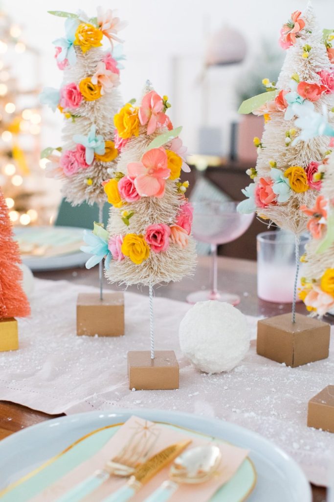 bottle brush trees decorated with flowers used as a centerpiece